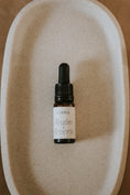 Load image into Gallery viewer, bottle of realm of reverie essential oil blend by Cerita on neutral ceramic dish