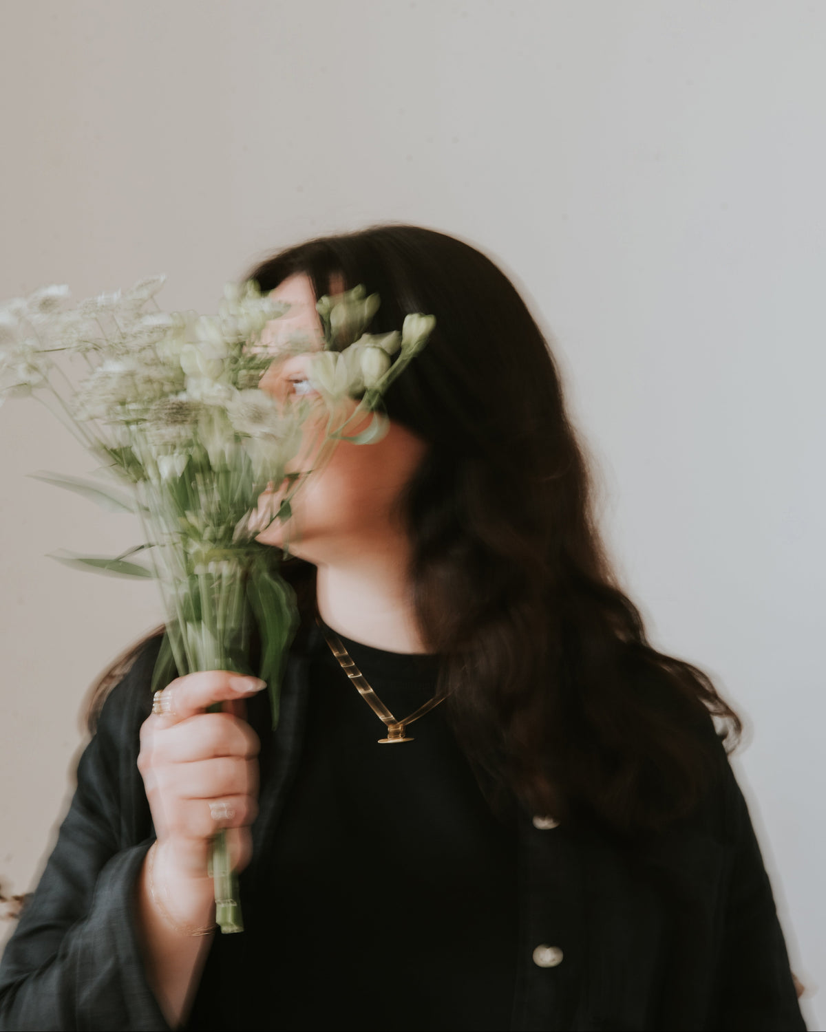 female founder holding a bouquet of wildflowers against a plain background