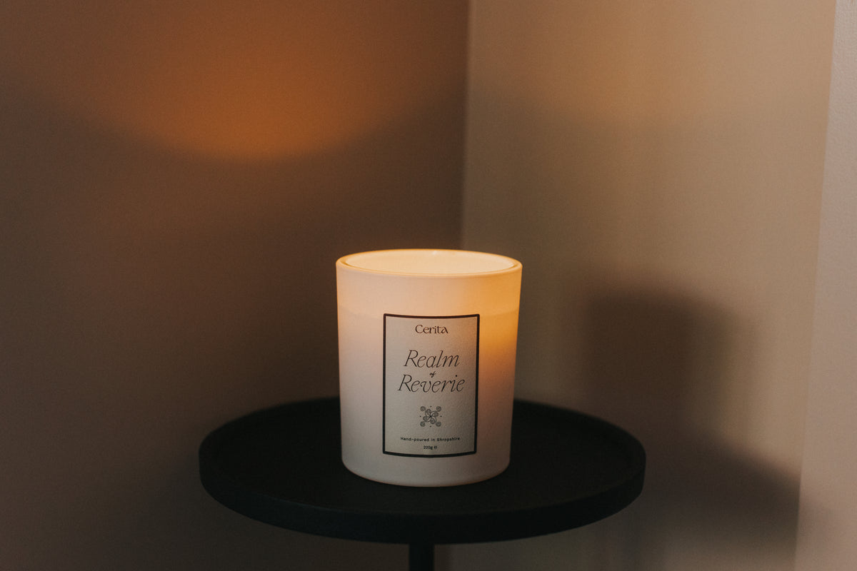 cerita essential oil candle lit on a black pedestal table neutral background