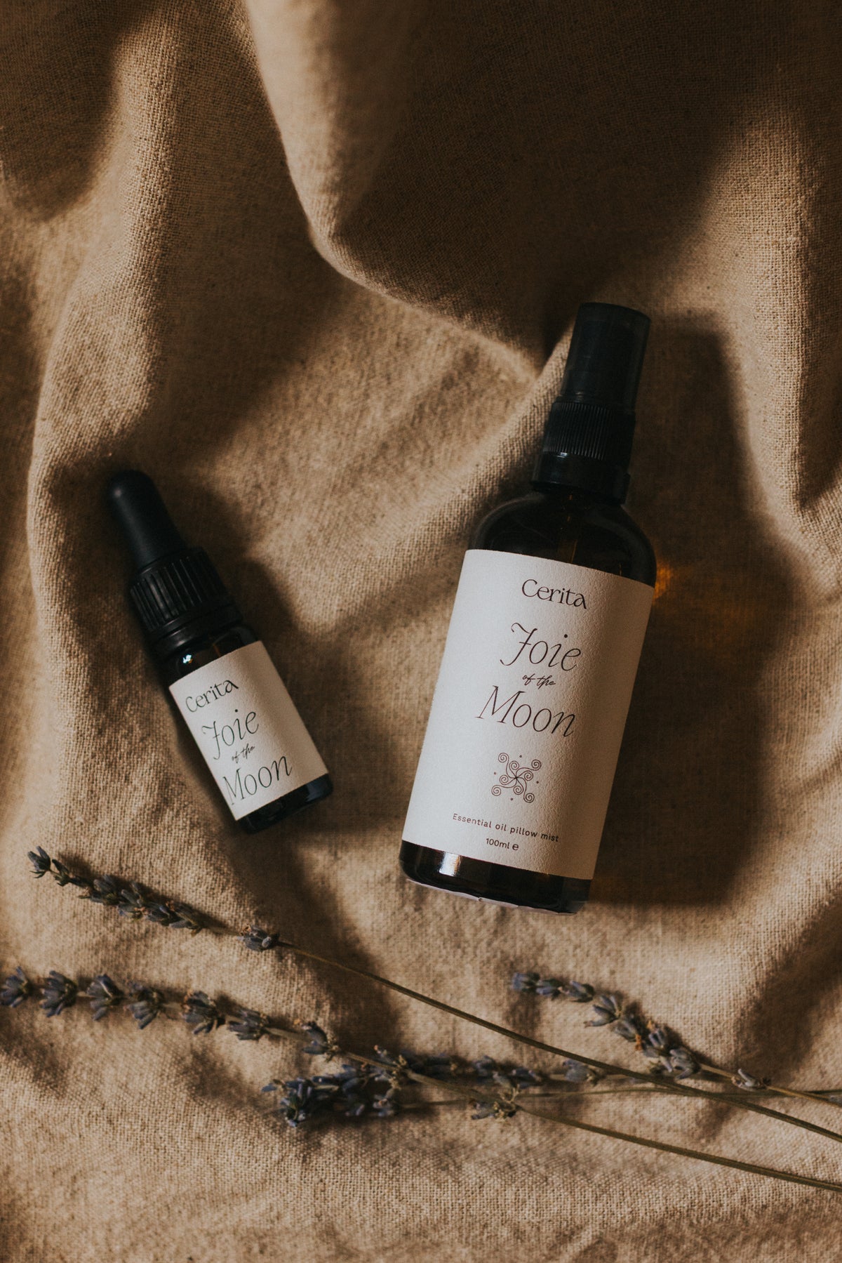 cerita essential oil blend and pillow mist bottles on neutral background with dried lavender sprigs