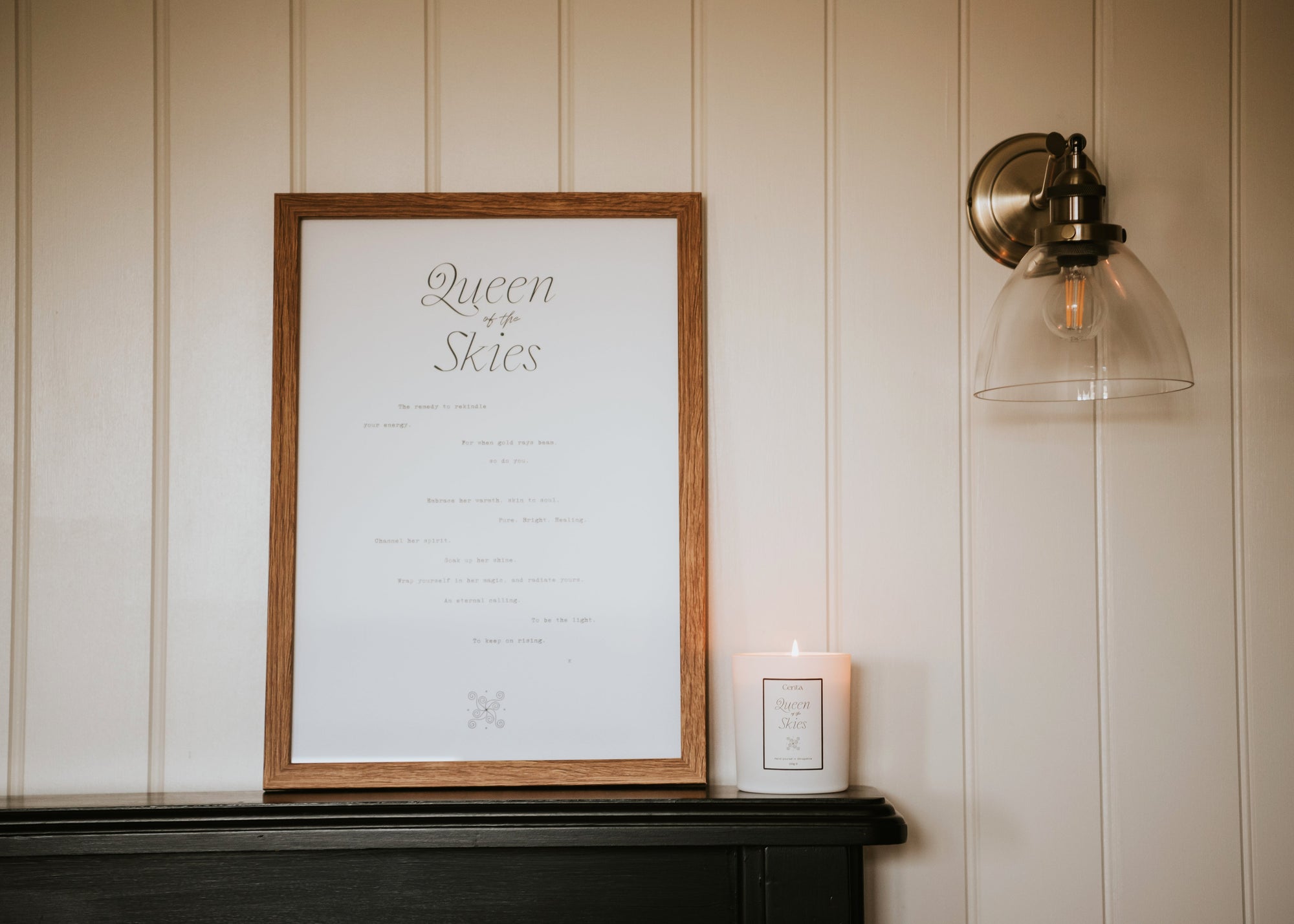 framed queen of the skies art print and lit essential oil candle by Cerita in neutral interior setting