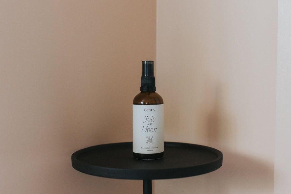 bottle of essential oil pillow mist on minimal black pedestal table with neutral background