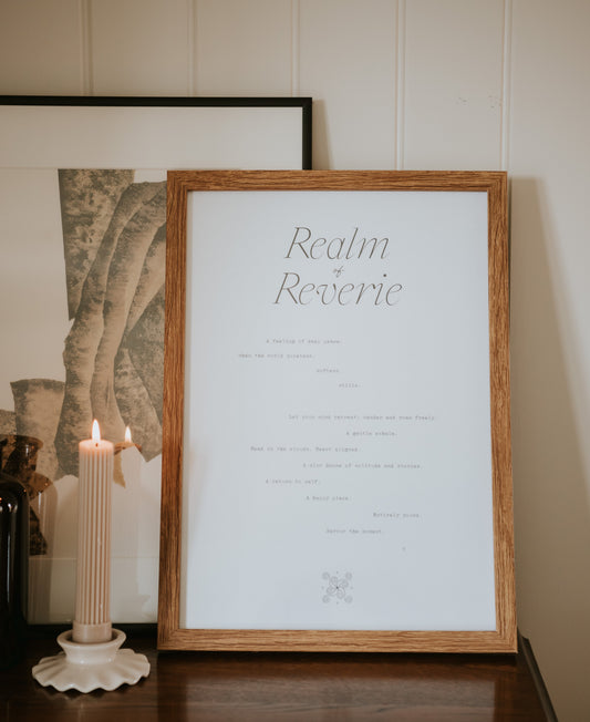 minimal typography a3 paper art print realm of reverie by Cerita in wooden frame on dresser with candle in neutral interior setting