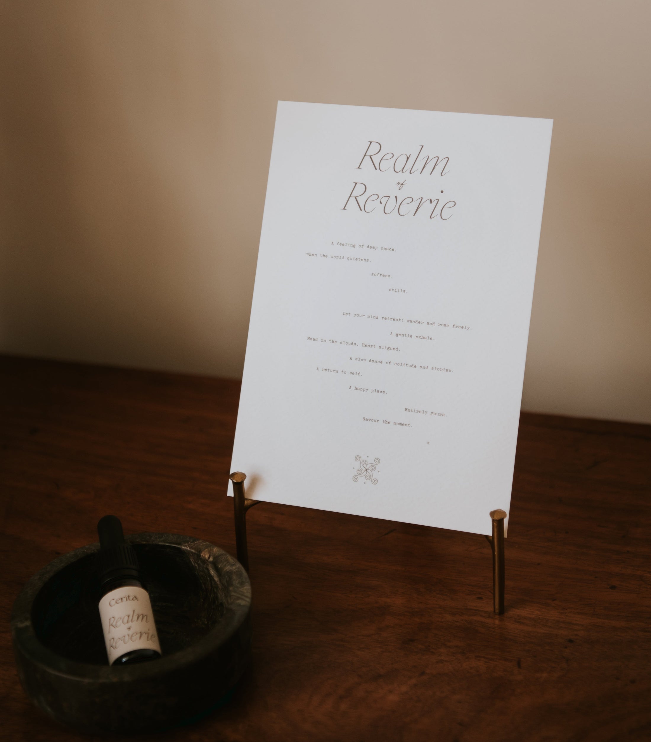 minimal typography a5 paper art print realm of reverie by Cerita on gold metal stand on wooden surface