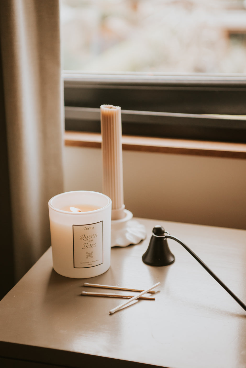 queen of the skies aromatherapy candle by Cerita on neutral dressing table with matches